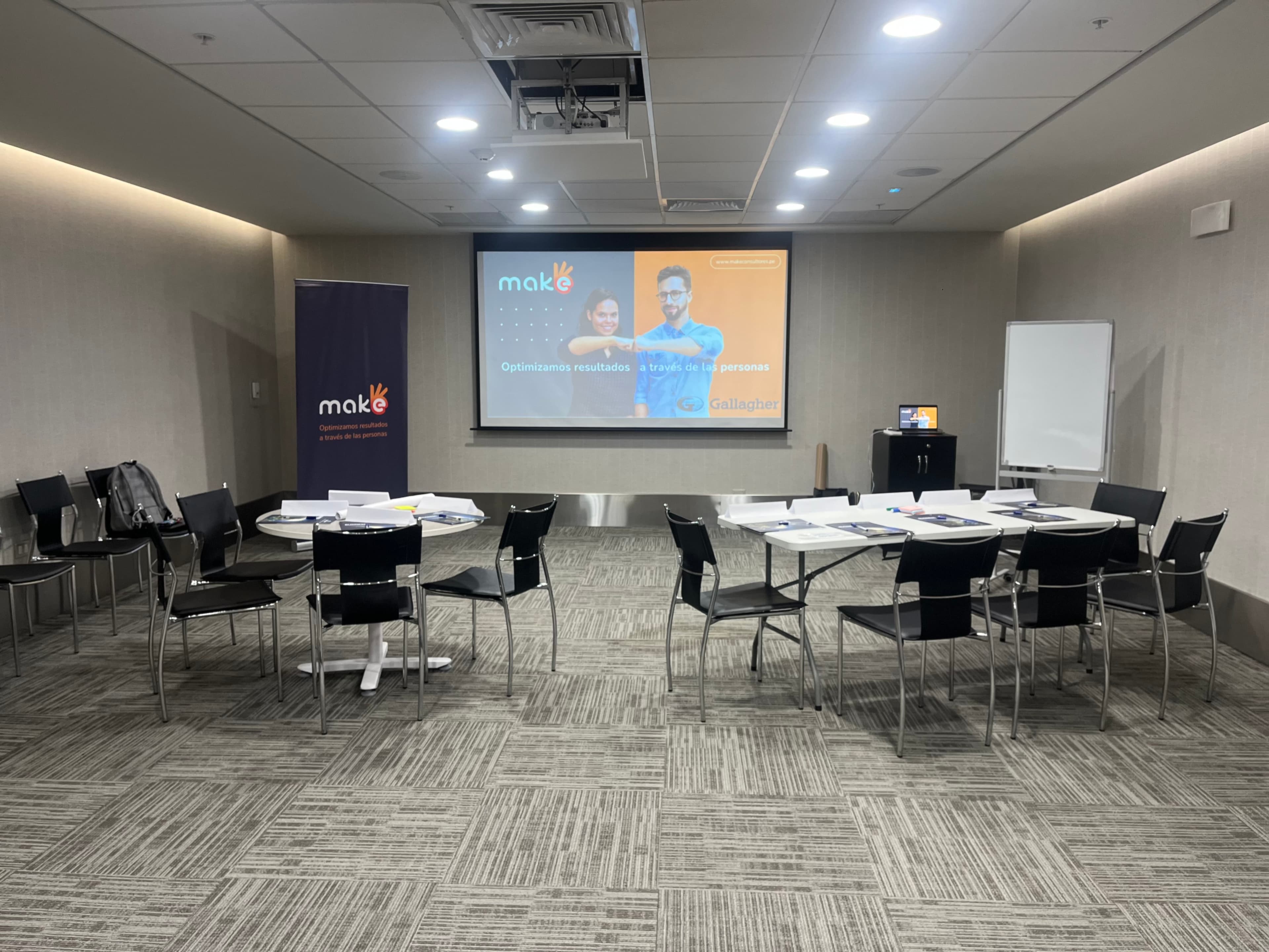 Meeting room featuring tables, chairs, and a projection screen displaying a presentation.